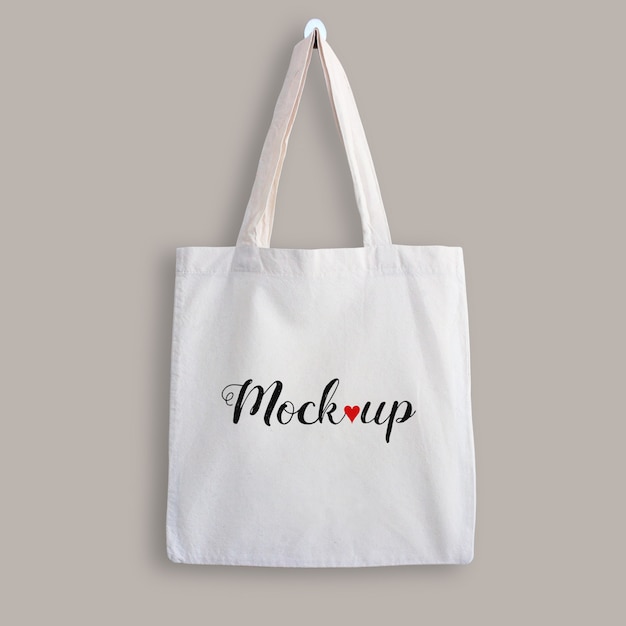 PSD mockup of a white cotton tote bag hanging on a wall