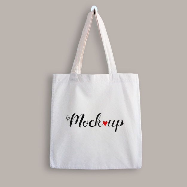 Mockup di una tote bag di cotone bianco appesa a un muro