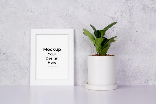 Mockup wit frame verticaal en planten in pot op tafelblad thuis, mock-up poster voor presentatie op bureau, uw ontwerp voor galerijfoto en afbeelding, randsjabloon en decoratie voor reclame.