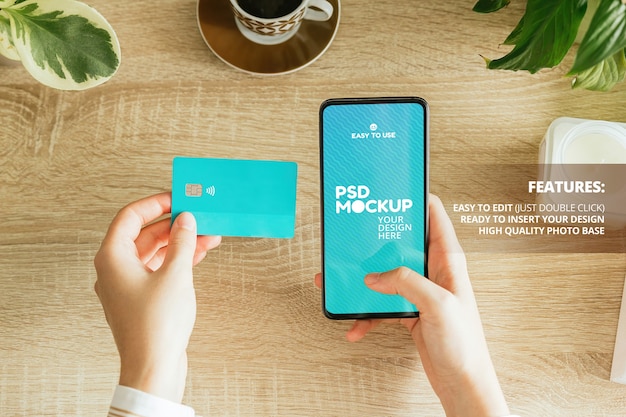 PSD mockup di una donna che tiene un telefono e una carta di credito sul tavolo