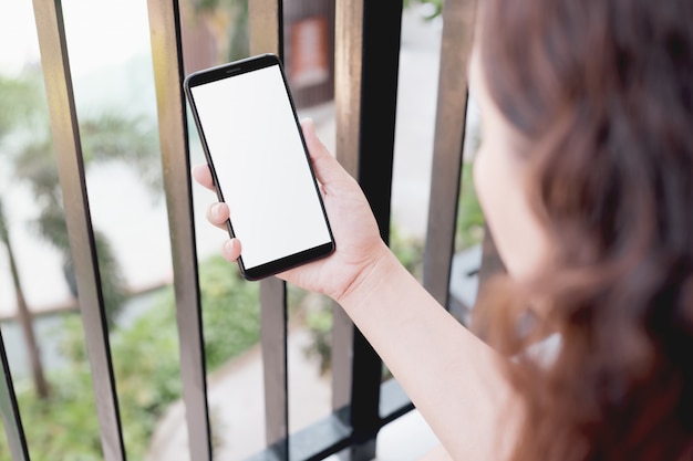 Modello di una donna che per mezzo dello smart phone con lo schermo bianco in bianco