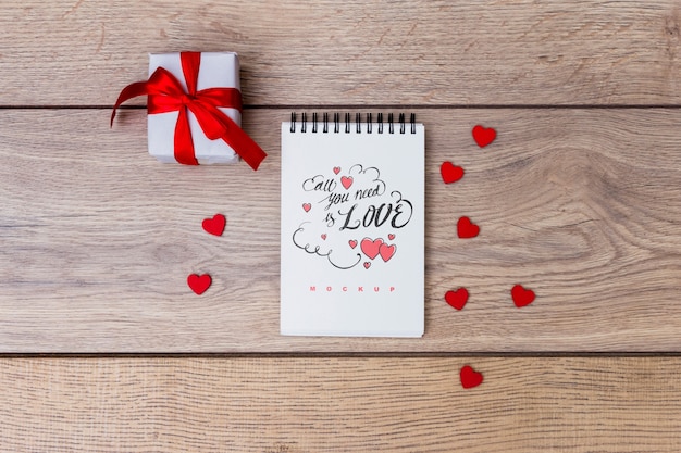 Mockup di blocco note accanto alla confezione regalo per San Valentino