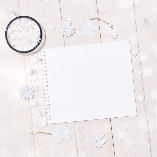 PSD notepad mockup with white decorations on wood table