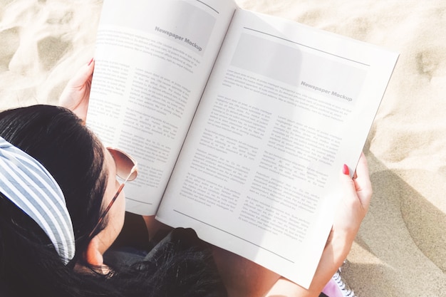 Open newspaper in girl's hands beach scene mockup