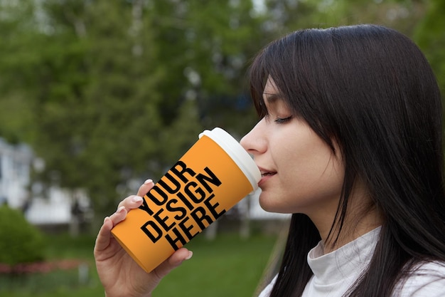 Oranje grote papieren koffiekop meisje drinken koffie close-up veranderlijke kleur mockup psd