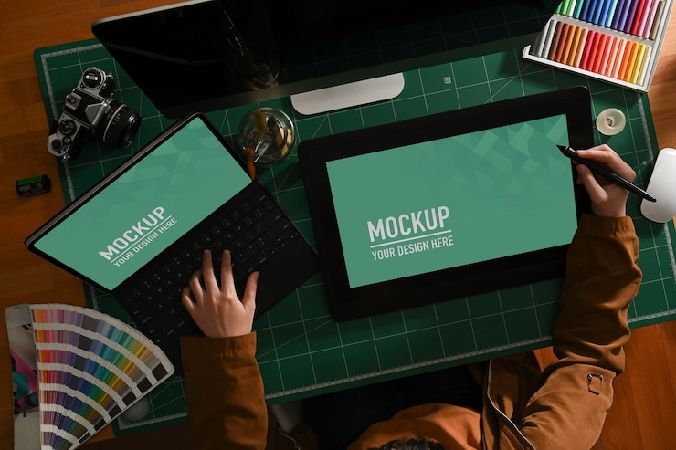PSD overhead shot of female graphic designer working with mock up tablet and laptop on computer desk