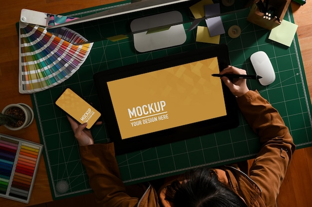 Overhead shot of female graphic designer working with mock up tablet and smartphone