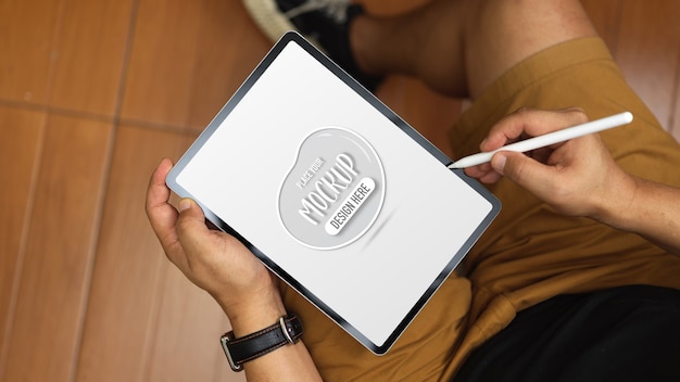 PSD overhead shot of young man working with mock up tablet while sitting in his office room