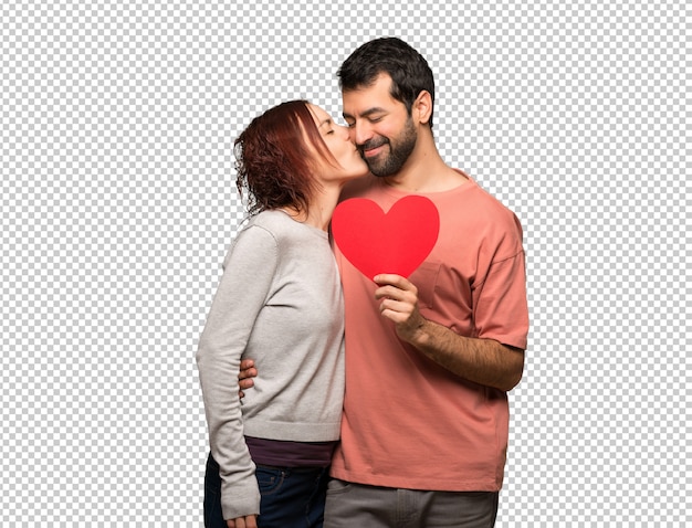 Paar dat in valentijnskaartdag een hartsymbool en het kussen houdt