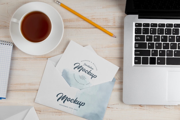 Paper invitation mock-up with watercolor design and laptop