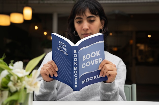 PSD person holding a book with mock-up cover