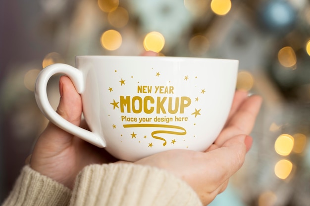 Person holding cup with defocused christmas tree