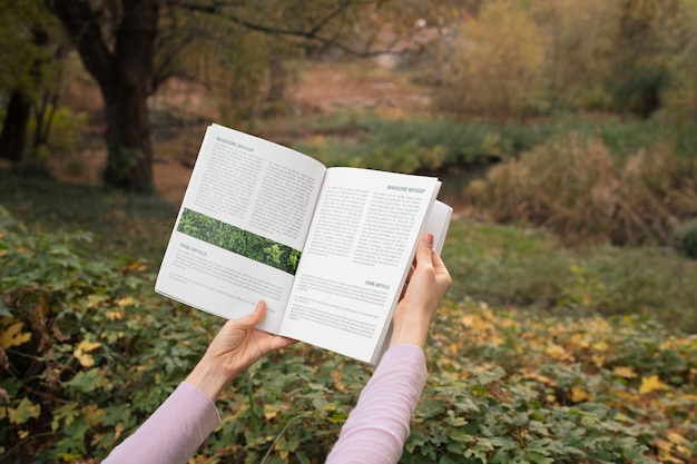 PSD person holding paper magazine outdoors in nature