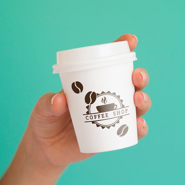 Person holding up a coffee paper cup on blue background