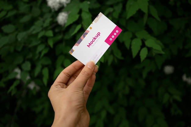 Person holding visit card mock-up in hand with plants background