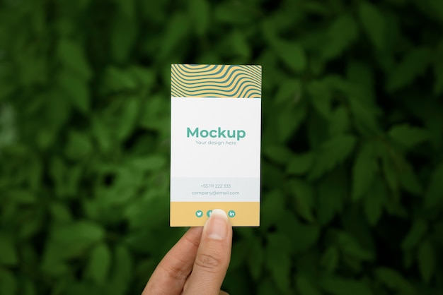 PSD person holding visit card mock-up in hand with plants background