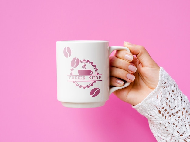 PSD person holding white mug mock-up on pink background