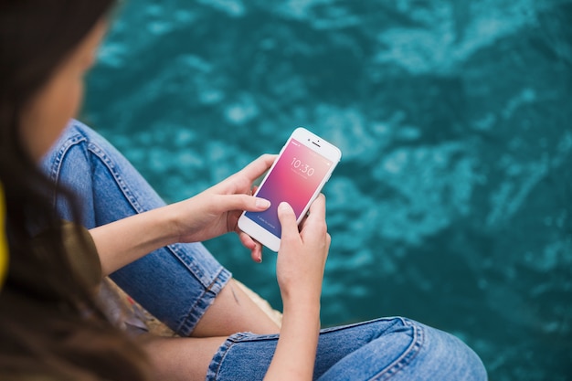 Person using smartphone mockup on sea background