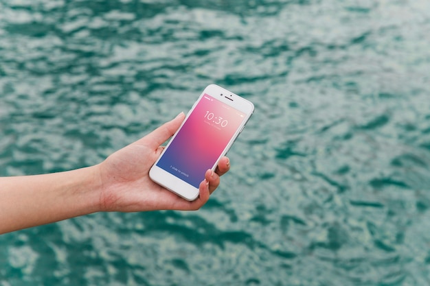 PSD person using smartphone mockup on sea background