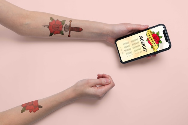 Persona con il modello del tatuaggio sulle braccia che tengono lo smartphone