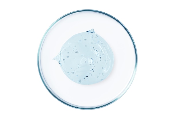 Petri dish with a drop and a smear of a transparent gel or serum on an empty background