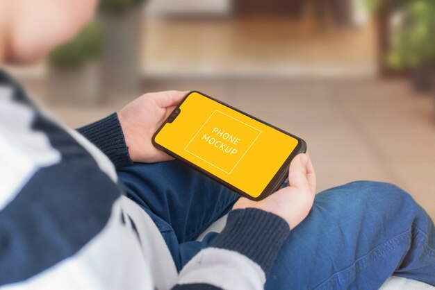 PSD phone mockup in boy hands. horizontal position.