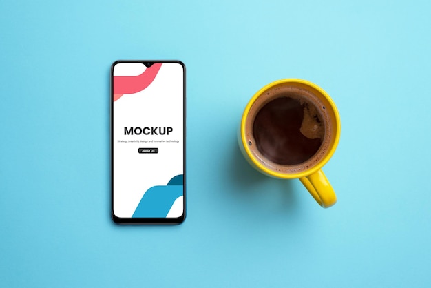 PSD phone mockup and coffee mug on clean blue surface