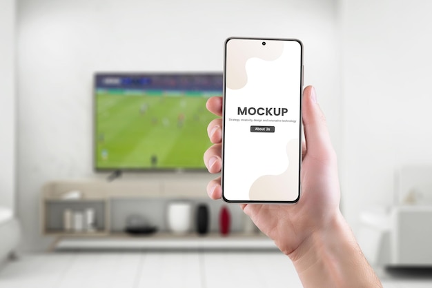 Phone mockup in hand with soccer game on tv in background