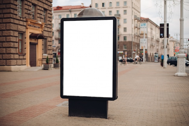 Photo of a large billboard that stands on the street, where many people walk