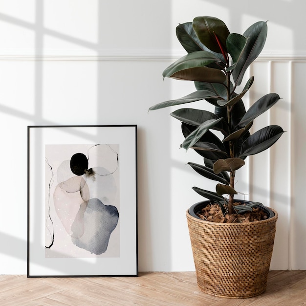 PSD picture frame mockup by a rubber plant on a wooden floor