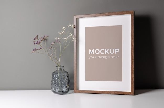 picture frame mockup over grey wall with dry flowers in glass vase