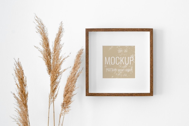 picture frame mockup on white wall with dry plant decorations