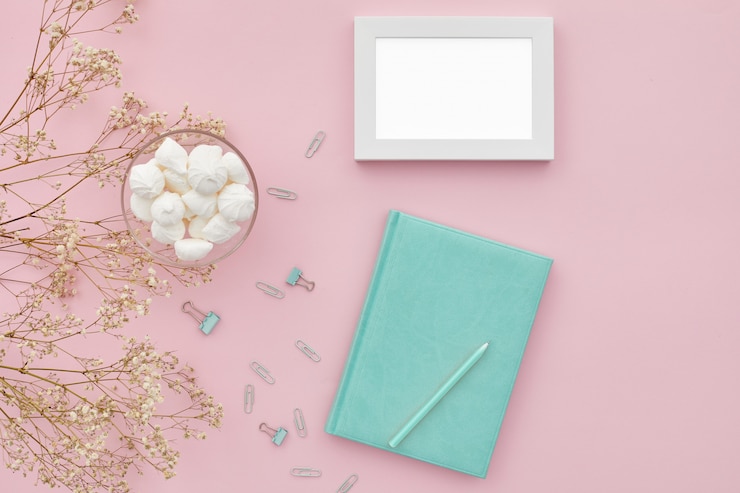 PSD plat lag bloemen en een dagboek op roze tafel, bovenaanzicht. mockup