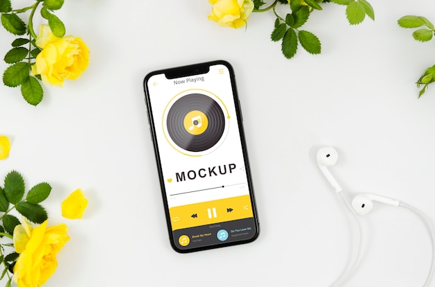 Plat lag smartphone mock-up met bloemen en oortelefoons