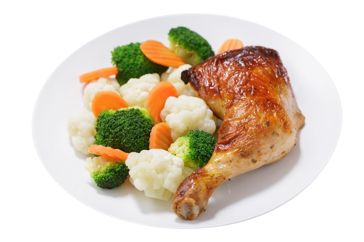PSD plate of baked chicken leg with vegetables isolated on transparent background