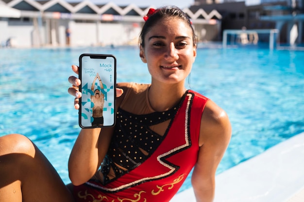 PSD pływaczka trzymająca makietę smartfona na basenie