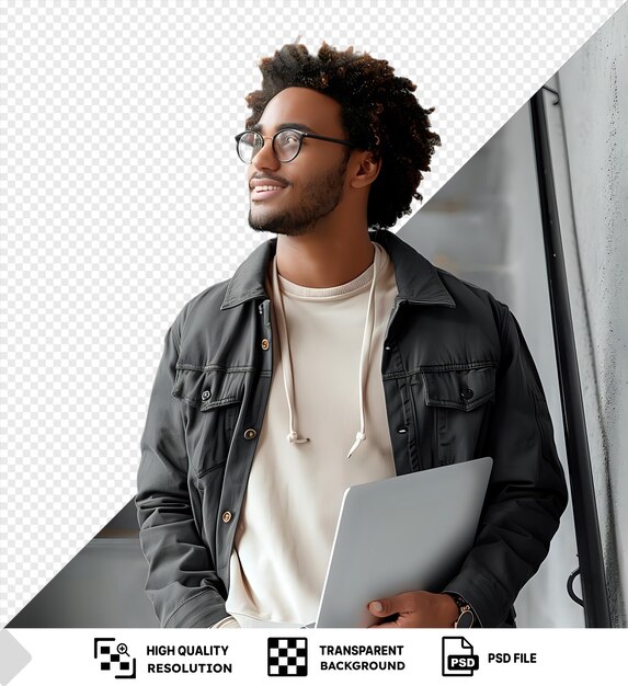 PSD potrait wellbeing a man with curly hair and black glasses stands in front of a gray and white wall holding a silver laptop in his hand he wears a black jacket and a png