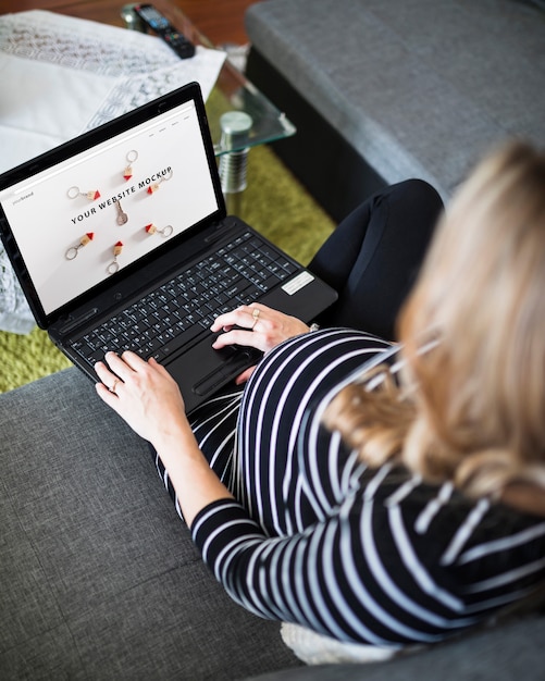 Pregnant woman on couch using computer