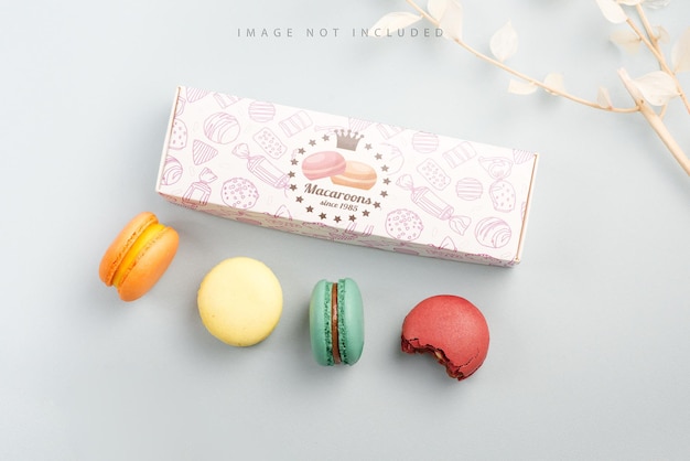 Present box mockup and colorful macarons on a blue background with dry branch