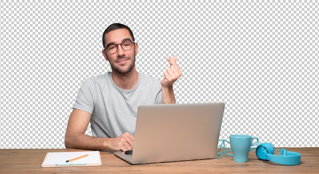 PSD satisfied young man sitting at his desk and doing a gesture of money with his hand