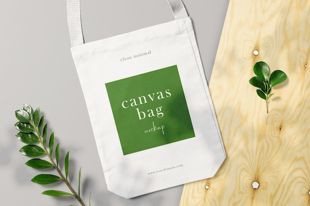 Schone minimale canvas tas mockup op achtergrond met houten plaat en bladeren psd-bestand