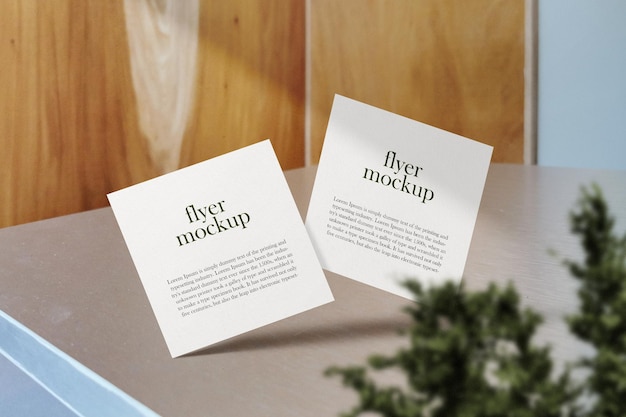 Schone minimale vierkante flyer mockup drijvend op tafel met plant PSD-bestand