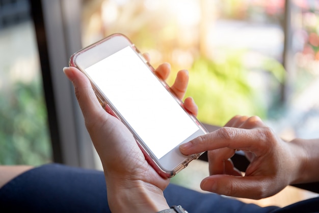 Selekcyjna ostrość kobiety wręcza używać mobilnego smartphone zamazującego tło