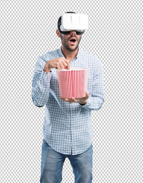 Потрясенный молодой человек, используя очки виртуальной реальности с попкорном
