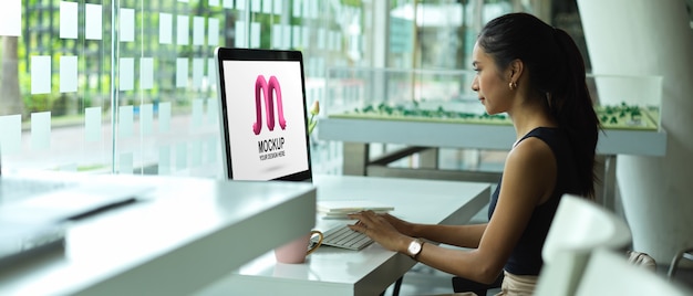 Side view of female office worker working with mockup computer screen