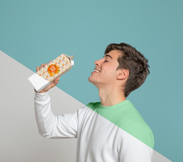 Side view of man drinking out of juice carton