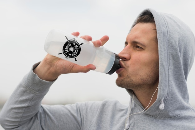 Side view of man drinking water while working out