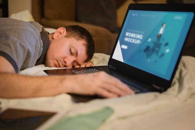 PSD side view of man falling asleep while working on laptop