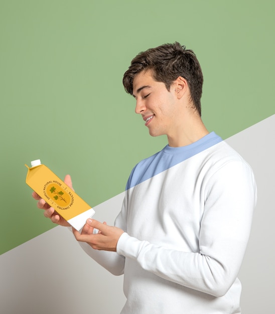 Side view of man holding juice carton