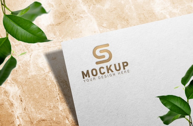 Mockup semplice e lussuoso con logo in lamina d'oro impresso su carta bianca pressata su sfondo di marmo